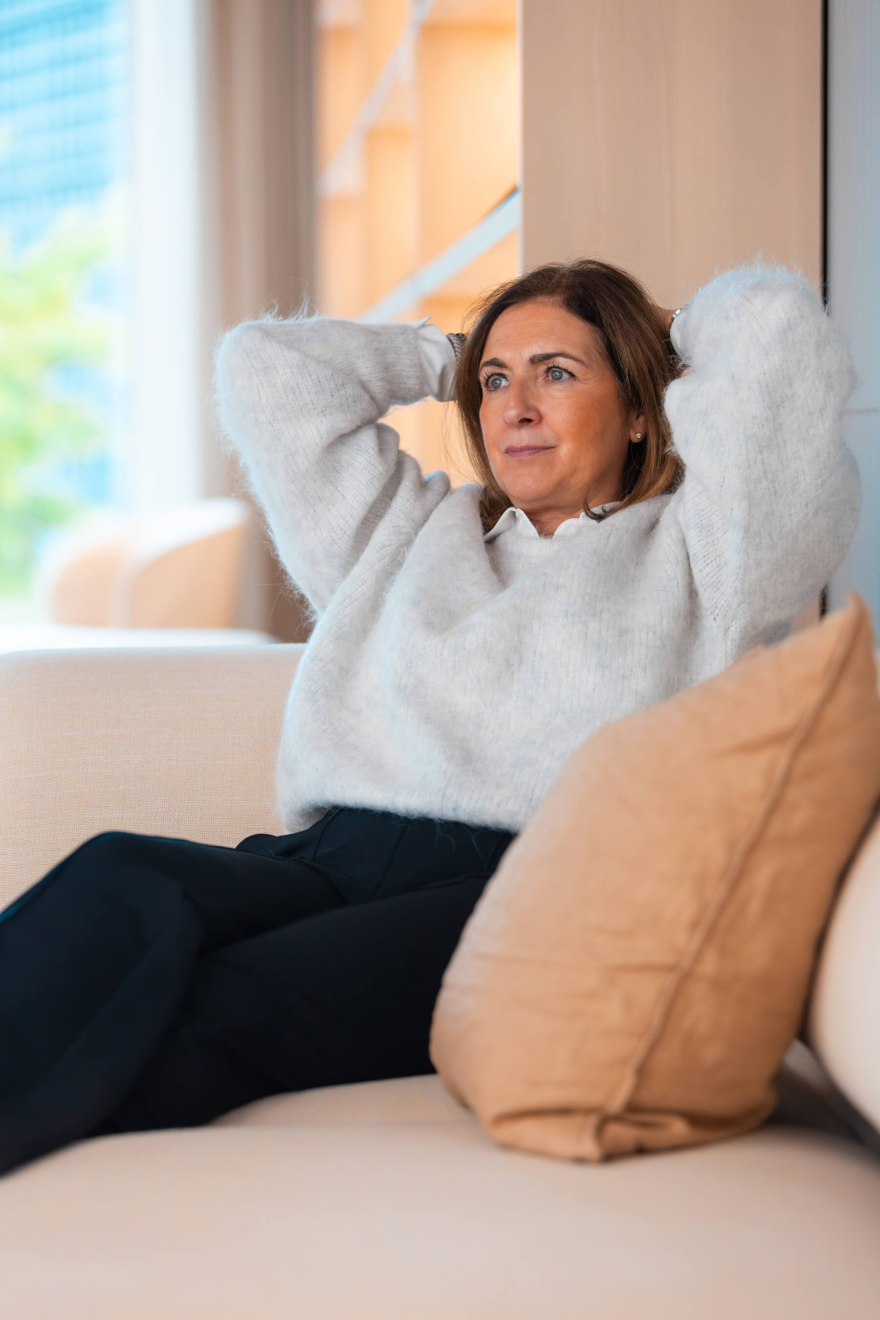 Claudia Jung sitzt entspannt auf einem Sofa, die Hände hinter dem Kopf