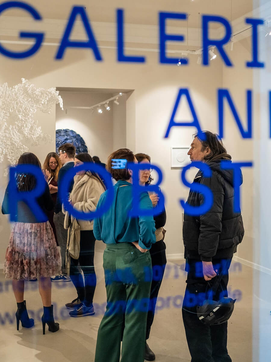 Galerie Anna Probst: Gäste bei einer Eröffnung hinter der beschrifteten Fensterfront